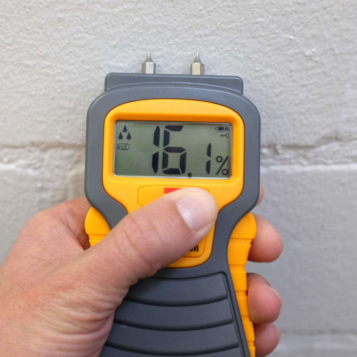 Technician using a moisture meter to inspect a wall for hidden water damage
